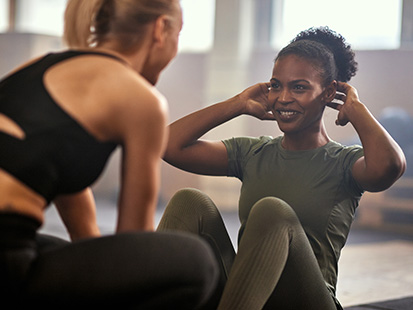Women doing sit ups with friend assisting